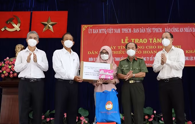 El ex vice primer ministro permanente Truong Hoa Binh (segundo desde la izquierda) entrega a estudiantes de la etnia Cham dispositivos al servicio del aprendizaje en línea. (Fotografía: Nhan Dan)