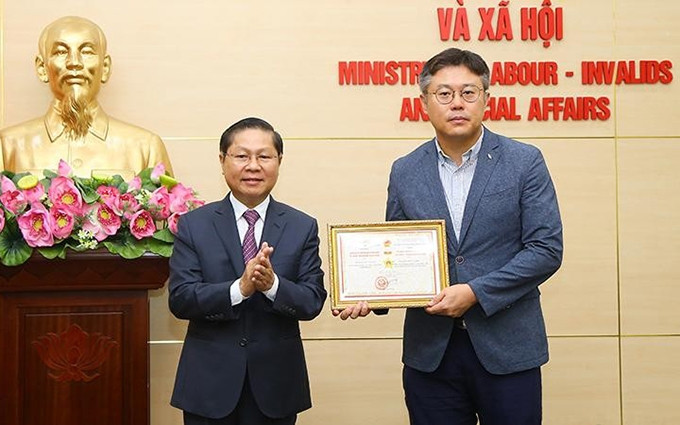 El viceministro de Trabajo, Inválidos de guerra y Asuntos Sociales de Vietnam Le Tan Dung entrega el sello conmemorativo al jefe de la Oficina de Representación de la Agencia Surcoreana para el Desarrollo de Recursos Humanos en Vietnam, Kang Byung Joo. (Fotografía: Molisa)