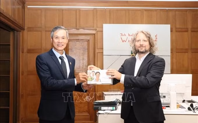 El embajador de Vietnam acreditado en Alemania, Nguyen Minh Vu, recibe la donación del secretario de estado del Departamento de Economía, Energía y Empresas Públicas del Senado de Berlín, Christian Rickerts. (Fotografía: VNA)