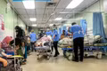 Un auxiliar médico (vestido con pantalones y zapatos negros) traslada a un paciente en una camilla por el pasillo, una zona pública, del departamento de urgencias y traumatología del Hospital Raja Permaisuri Bainun, en Ipoh, Perak (Foto: codeblue.galencentre.org)