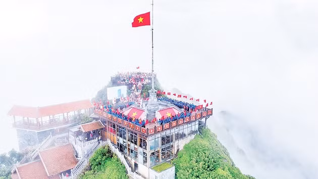 Los jóvenes realizan el saludo a la bandera y entonan el himno nacional en la cima del Fansipan.