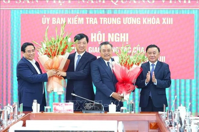 El primer ministro Pham Minh Chinh, y el miembro permanente del Secretariado, Tran Cam Tu, entregaron flores para fecilitar a los compañeros Tran Sy Thanh y Nguyen Duy Ngoc. (Foto: VNA)