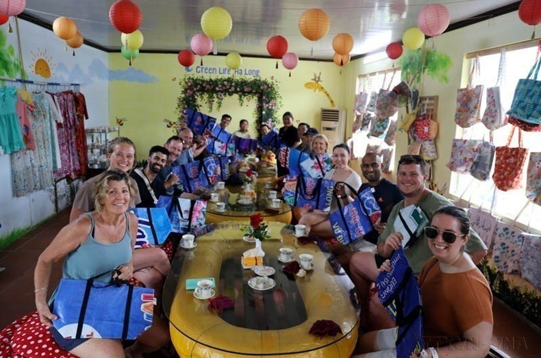 Turistas extranjeros muestran su entusiasmo por los bolsos hechos con lonas de plástico recicladas de la cooperativa Green Life Ha Long, en la provincia norteña de Quang Ninh. (Foto: VNA) 1-5197.jpg