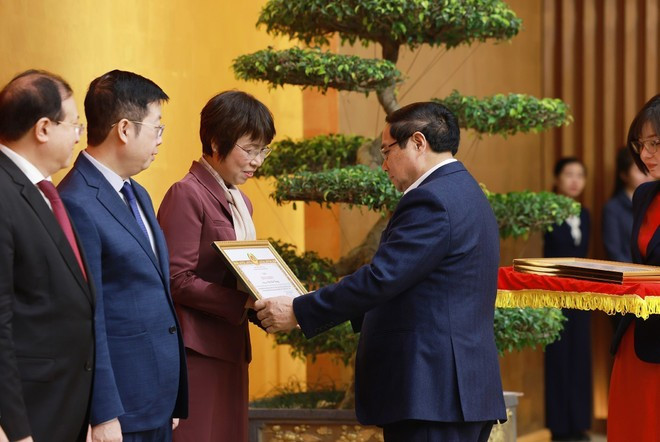 El primer ministro Pham Minh Chinh entrega certificado de reconocimiento del Comité del Partido del Gobierno a la directora general de la Agencia Vietnamita de Noticias, Vu Viet Trang. (Foto: VNA)
