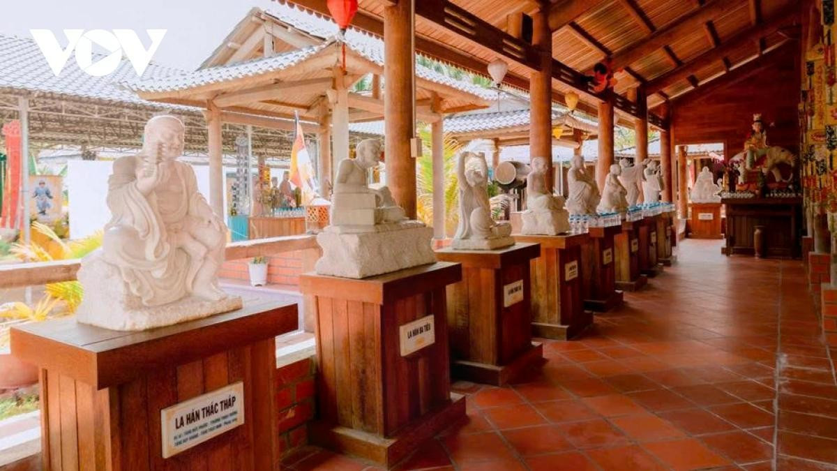 Un largo y silencioso corredor sostenido por columnas de cocoteros centenarios. A ambos lados se alinean estatuas de arhats talladas en piedra blanca.