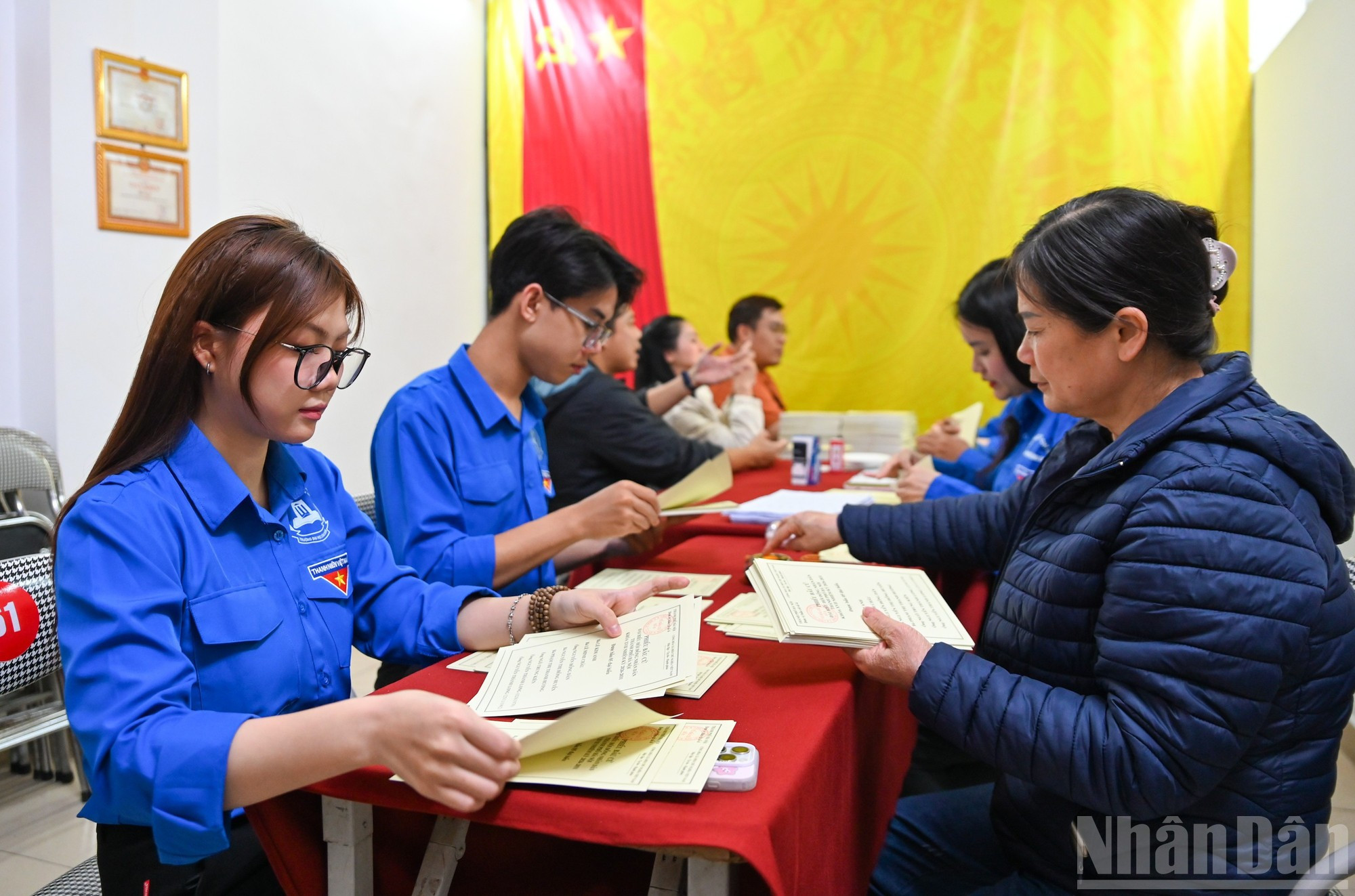 En la sala de reuniones de la zona residencial 58, grupo vecinal 63, perteneciente al colegio electoral número 2 del barrio de Dong Da, funcionarios locales y jóvenes voluntarios sellan cada papeleta de voto.