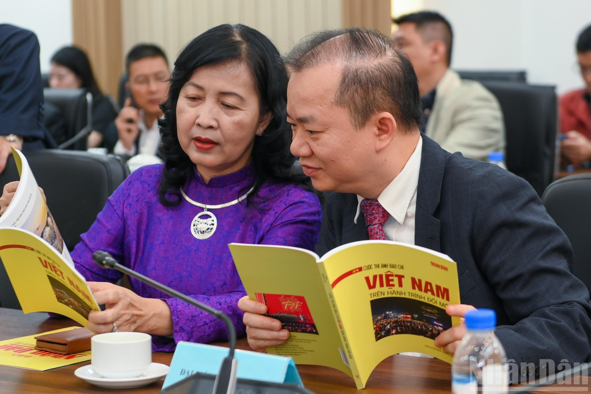 Tran Thi Thu Dong y el profesor asociado y doctor Bui Hoai Son, miembro permanente del Comité de Asuntos Socioculturales de la Asamblea Nacional, revisan las obras galardonadas.