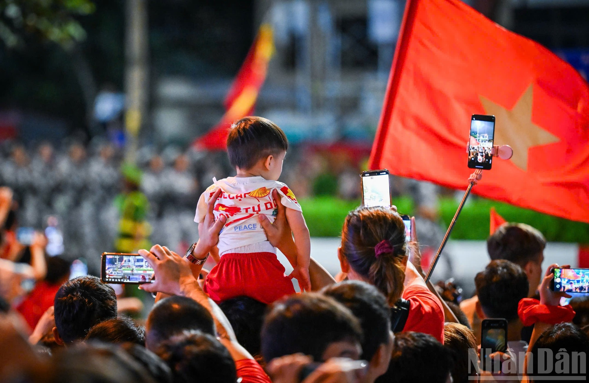 Un niño es llevado por sus familiares para unirse al ambiente alegre y entusiasta del ensayo general.