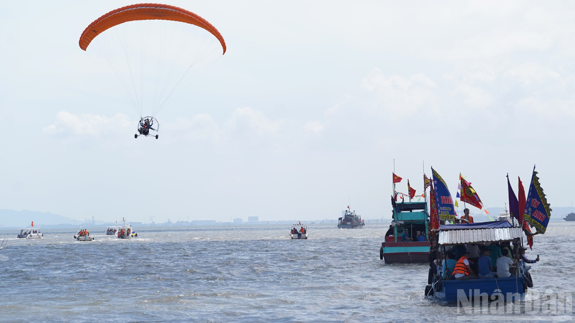 Banderas festivas de múltiples colores engalanan a los barcos y ondean al viento, creando una escena animada y vibrante.