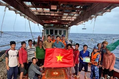 Las fuerzas de seguridad marítima de Ciudad Ho Chi Minh entregan la bandera nacional y difunden medidas preventivas contra la pesca INDNR a los marineros. (Foto: VNA)