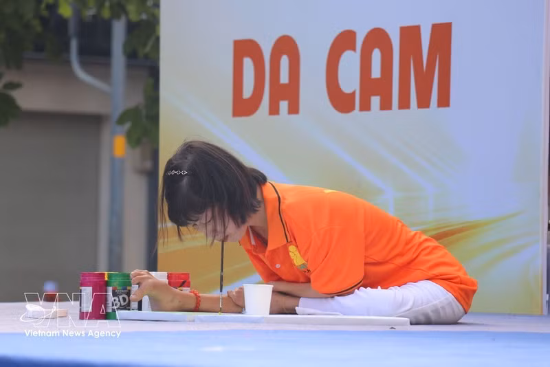 Una víctima del Agente Naranja pinta con su boca en la cita. (Foto: VNA)