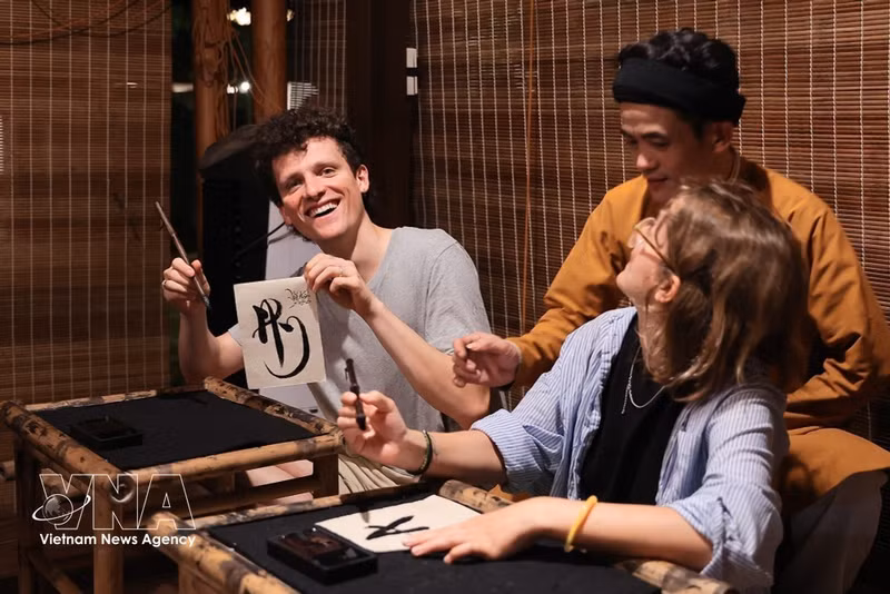 Los turistas extranjeros aprenden técnicas de caligrafía en el Templo de la Literatura. (Foto: VNA)