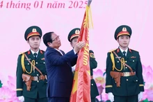 El primer ministro de Vietnam, Pham Minh Chinh, coloca la insignia “Héroe de las Fuerzas Armadas Populares” en la bandera tradicional de las fuerzas armadas de Ciudad Ho Chi Minh. (Foto: VNA)