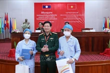 Nguyen Xuan Kien, director de la Academia de Medicina Militar de Vietnam, entrega obsequios a los dos pacientes laosianos. (Fotografía: VNA)