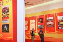 Turistas internacionales visitan una exposición por el aniversario 95 de la fundación del Partido Comunista de Vietnam. (Foto: VNA)