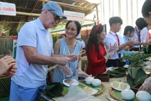 Turistas extranjeros entusiasmados con la forma de envolver el Banh Chung.