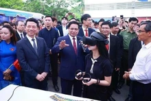 El primer ministro Pham Minh Chinh y otros delegados visitan las áreas de exhibición que presentan productos innovadores y de transformación digital de universidades y empresas. (Foto: VNA)