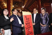 El primer ministro de Vietnam, Pham Minh Chinh, obsequia una caligrafía con palabras vietnamitas a su homólogo laosiano, Sonexay Siphandone. (Foto: VNA)