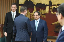 El primer ministro Pham Minh Chinh saluda a los miembros que acompaña al ministro de Asuntos Exteriores y Comercio Exterior de Hungría, Szijjarto Peter.