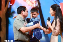 El primer ministro Pham Minh Chinh alentó a Nguyen Quoc Bao, quien perdió a su padre y su hermana mayor por las inundaciones en la comuna de Yen Thuan, distrito de Ham Yen, provincia de Tuyen. Quang. (Foto: VNA)