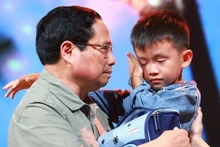 El primer ministro entrega obsequio a un niño cuyos familiares fallecieron por el tifón Yagi. (Foto: VNA)