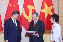 El secretario general del Partido Comunista de Vietnam, To Lam, entrega respetuosamente al secretario general del Partido Comunista y presidente de China, Xi Jinping, un libro de fotografías de la Agencia de Noticias de Vietnam, que incluye fotos típicas e impresionantes de las cinco visitas de Xi Jinping al país indochino. (Foto: VNA)