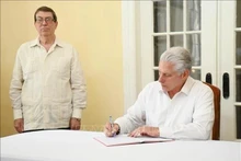 El primer secretario del Comité Central del Partido Comunista y presidente de Cuba, Miguel Díaz-Canel Bermúdez, escribe en el libro de condolencias. (Foto: VNA)