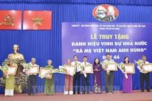 El presidente del Comité Popular de Ciudad Ho Chi Minh, Phan Van Mai, entrega título póstumo "Madres Heroicas" a representantes de las familias.(Fotografía: thanhuytphcm.vn)