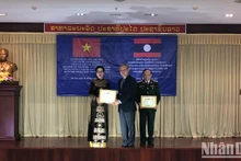 El jefe de la Comisión de Relaciones Exteriores del Comité Central del Partido Revolucionario Popular de Laos, Thongsavanh Phomvihane, entrega la Orden de la Amistad a individuos vietnamitas. 
