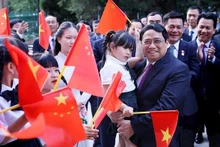 El primer ministro de Vietnam, Pham Minh Chinh, y representantes de la comunidad de connacionales en China (Fotografía: VNA)