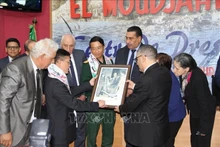 El embajador vietnamita en Argelia, Tran Quoc Khanh, regala al director general del periódico El Moudjahid, Brahim Takheroubt, una foto del General Vo Nguyen Giap entregando la bandera de Vietnam al ministro de Defensa de Argelia en 1976 (Foto: VNA) 