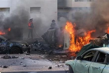 Las personas apagan incendios en coches tras un ataque con cohetes desde la Franja de Gaza en Ashkelon (Israel), el 7 de octubre de 2023. (Foto: AFP/VNA)