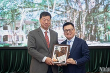 El presidente-editor del periódico Nhan Dan, Le Quoc Minh, entrega un regalo al presidente y director ejecutivo de la agencia de noticias surcoreana de Yonhap, Hwang Dae-il. (Foto: Son Tung)