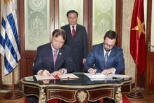 El presidente del Parlamento Vuong Dinh Hue en presencia de la firma de las actas del Comité conjunto de Cooperación Económica, Comercial y de Inversiones entre el ministro interino de Relaciones Exteriores de Uruguay, Nicolás Albertoni, (izquierda) y el viceministro de Industria y Comercio Do Thang Hai (Foto: VNA)
