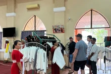 Visitantes extranjeros en una tienda de introducción de productos de brocado de la aldea artesanal de My Nghiep. (Foto: VOV)