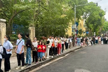 La mañana del 27 de abril, las hermanas Linh Chi y An Nhien (vestidas con camisetas de la bandera roja y estrellas amarillas), esperan su turno para recibir la publicación informativa especial del periódico Nhan Dan.