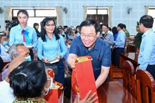 El presidente de la Asamblea Nacional, Vuong Dinh Hue, entrega regalos del Tet a los pobres.
