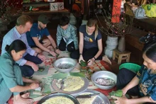 Turistas extranjeros participan en la elaboración de banh chung (pastel cuadrado de arroz glutinoso) (Fuente:VNA)