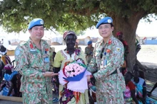 Representantes del hospital de campaña de segundo nivel número 4 de Vietnam regalan flores a una mujer sudsudanesa en ocasión del Día Internacional de la Mujer. 