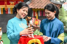 Ngo Phuong Ly (izquierda), esposa del secretario general del Partido Comunista de Vietnam, To Lam, presenta una marioneta de agua a Loo Tze Lui, cónyuge del primer ministro de Singapur, Lawrence Wong. (Foto: VNA)