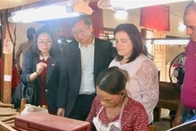 El embajador de Vietnam en Cuba, Le Quang Long, observa el meticuloso proceso de enrollar tabaco a mano. (Fotografía: VNA)