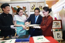 El primer ministro de Vietnam, Pham Minh Chinh, y su homóloga tailandesa, Paetongtarn Shinawatra, contemplan productos artesanales vietnamitas. (Fotografía: VNA)