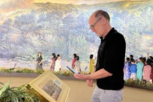 Un turista extranjero escanea el código QR para aprender sobre la pintura. (Fotografía: baodienbienphu.com.vn)