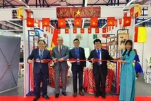 El embajador Tran Quoc Khanh (centro) y el consejero comercial Hoang Duc Nhuan (izquierda) cortan la cinta para inaugurar el pabellón de Vietnam en la feria. (Fotografía: VNA)