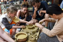 Turistas extranjeros hacen de alfarero en aldea tradicional de Vietnam