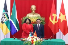 El miembro del Buró Político y permanente del Secretariado del Comité Central del PCV, Tran Cam Tu, y la vicesecretaria general del ANC de Sudáfrica, Nomvula Mokonyane, intercambian un documento de cooperación entre los dos Partidos. (Fotografía: VNA)