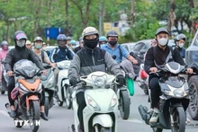 Motociclistas visten ropa abrigada y guantes al circular en la calle. (Fotografía: VNA)