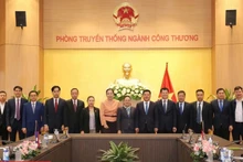 El ministro de Industria y Comercio, Nguyen Hong Dien (sexto desde la derecha), y la embajadora de Laos en Vietnam, Khamphao Ernthavanh (séptima desde la derecha), mantienen una sesión de trabajo. (Fotografía: tapchicongthuong.vn)