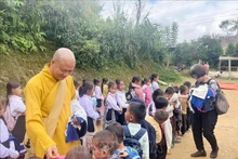 El venerable Thich Minh Quang, abad de la pagoda de Phat Tich en Vientián, obsequia a niños de familias afectadas por inundaciones en Houaphan. (Fotografía: VNA)