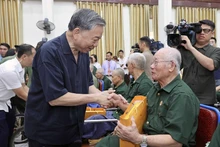 El presidente To Lam entrega regalos a los inválidos de guerra participantes en la reunión. (Fotografía: VNA)